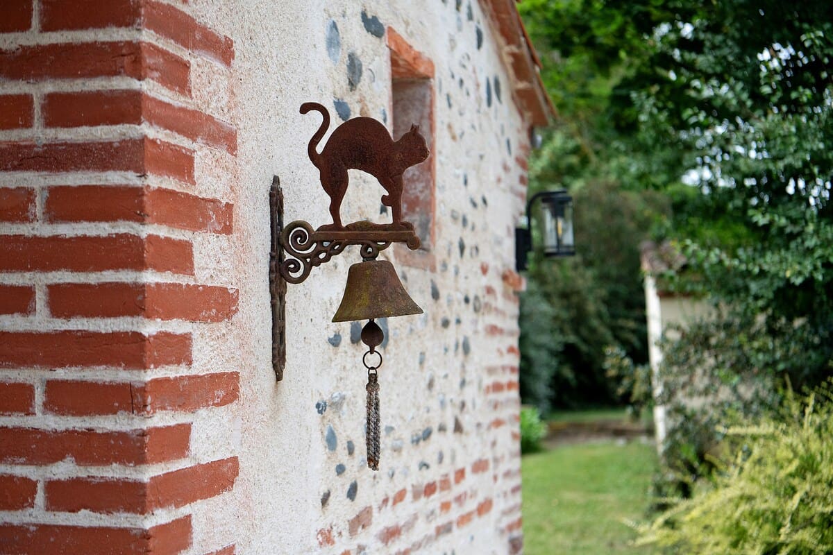 Mur en briques rouges et galets de rivière, et son coq en fer forgé